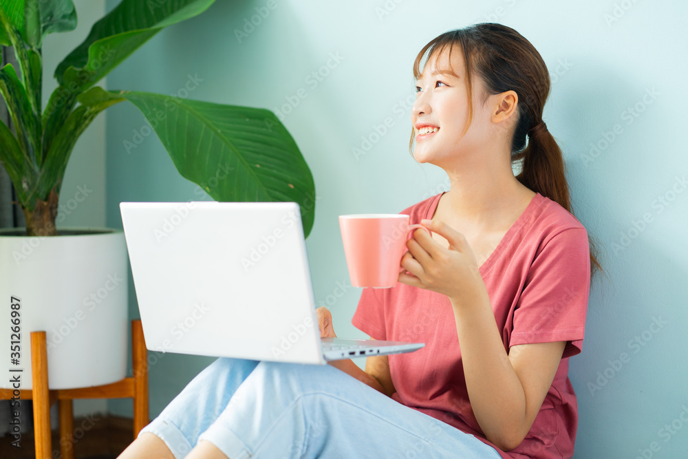 Asian woman sitting on the floor while she working from home Asian woman sitting on the floor while she working from home