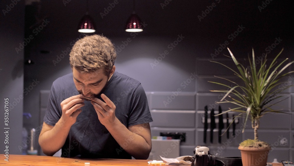 Attractive man makes a cigarette with tobacco and a piece of paper in