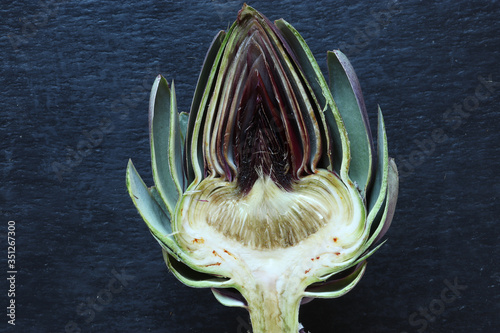Top view photography of a cut in halves artichoke on slate for food background