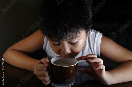 Young Asian boy drinking hot chocolate from a mug