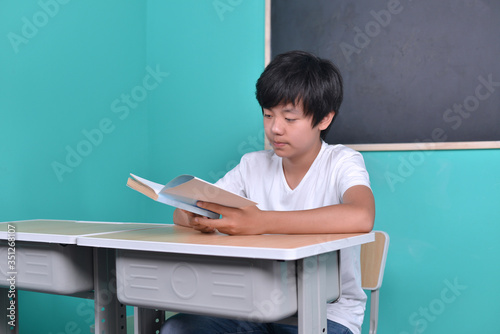 Smart Asian student reading book in classroom photo