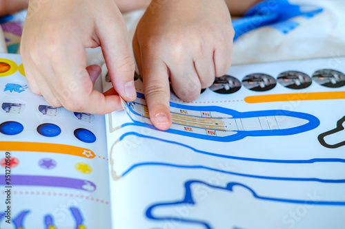 Child’s hand, Kid’s hand is sticking rocket sticker on space education activity book. Space education activity for school student.