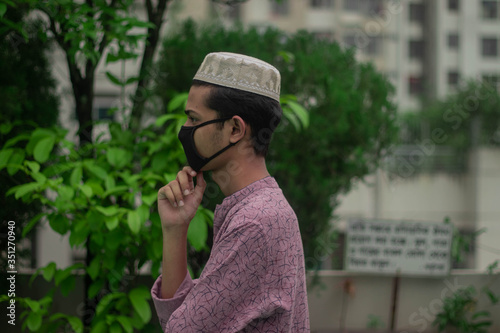 Muslim boy with traditional punjabi wears protective mask  while staying at home for quarantine due to the outbreak of coronavirus covid 19 pandemic.Home quarantine and health sign