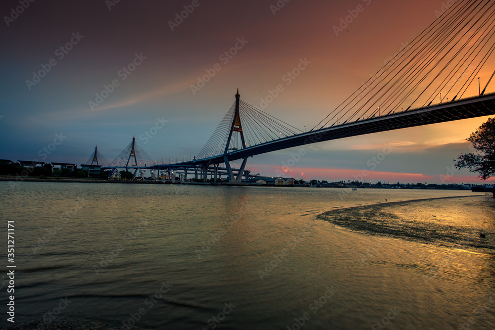 Fototapeta premium The blurred background of the twilight evening by the river, the natural color changes, the bridge over the river (Bhumibol Bridge) is one of the major transportation bridges in Bangkok, Thailand