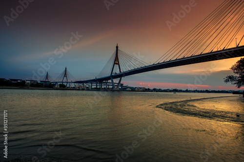 The blurred background of the twilight evening by the river, the natural color changes, the bridge over the river (Bhumibol Bridge) is one of the major transportation bridges in Bangkok, Thailand © bangprik
