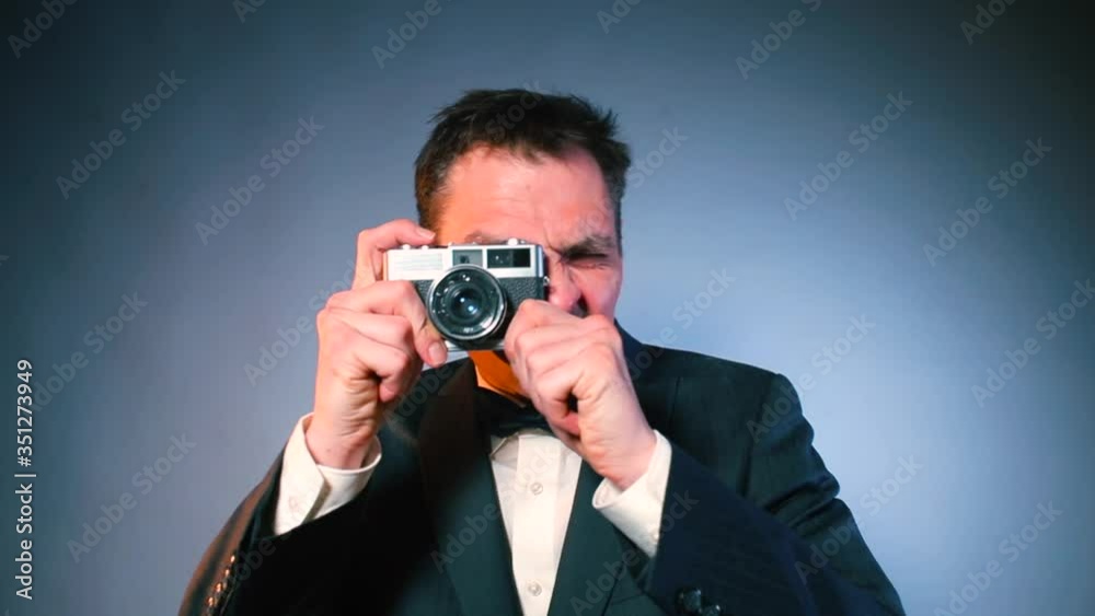 A young man who loves to take pictures, guest in suit, bow tie at a virtual wedding during quarantine lockdown. Film photography as a hobby in home isolation. A young man who loves to take pictures, guest in suit, bow tie at a virtual wedding during quarantine lockdown. Film photography as a hobby in home isolation.