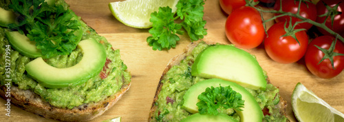 Slice of bread with guacamole made from avocado, tomato, lime, poarsley and garlic - close up  - banner design
