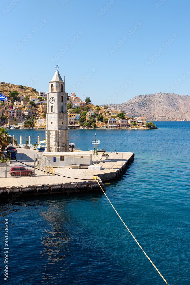 Clock tower on Symi island and view of the sea bay. Dodecanese islands, Greece