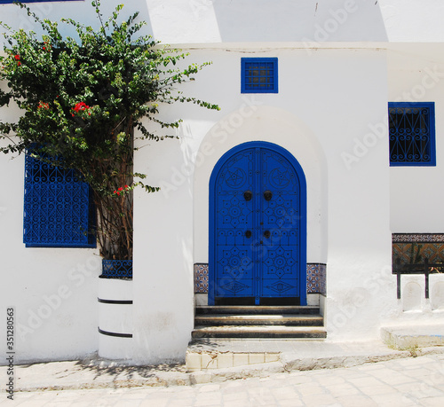 Traditional blue Tunisian metal door with a black pattern in a white building in the city of Sidi Bou Said in Tunisia in the summer on a sunny day