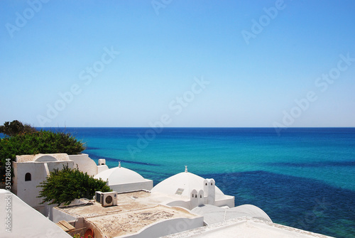 Azure sea, blue sky and white roofs of houses of the medina of Hammamet in Tunisia photo