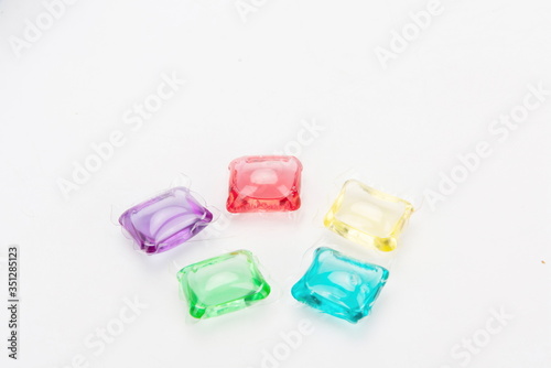 Laundry capsules of various colors in a white background