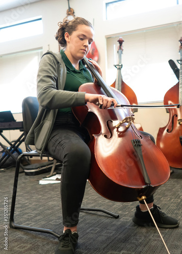 Teenage girl playing cello in classroom