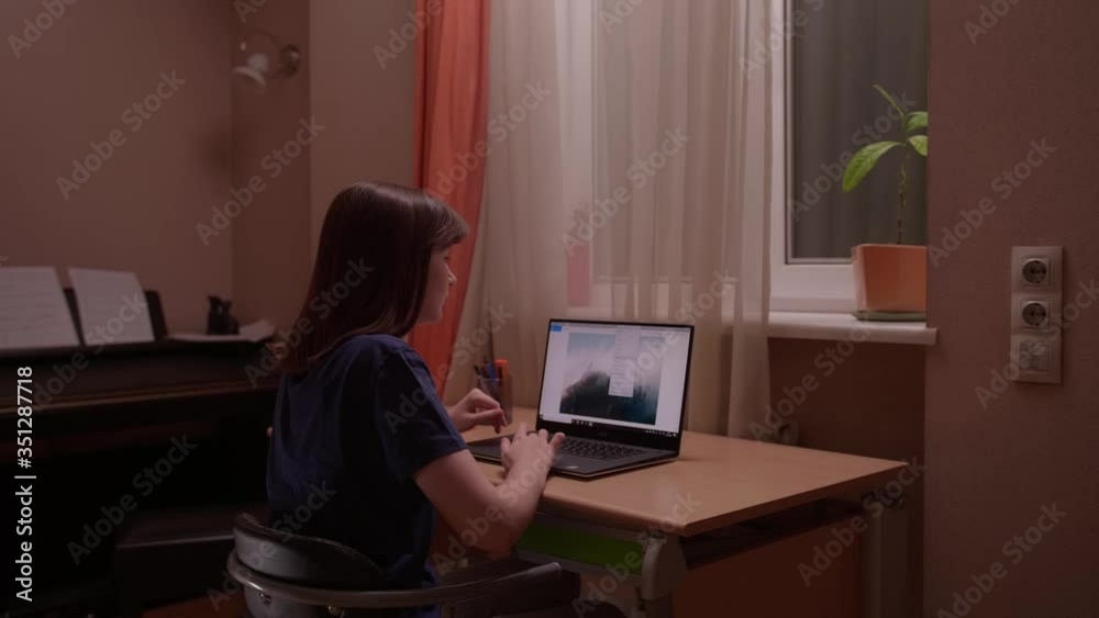 Millennial girl start working with laptop at home against night window. Beautiful young woman in comfortable room. With soft focus Millennial girl start working with laptop at home against night window. Beautiful young woman in comfortable room. With soft focus