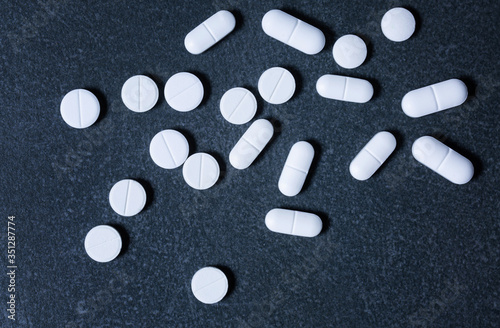 Pharmacy theme. White medicine tablets, antibiotic pills on a dark surface
