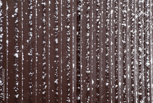 Iron brown fence covered with snow.