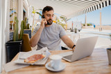 hombre joven trabajando mientras desayuna en una cafetería
