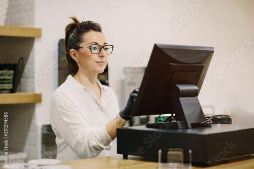 Business woman in a coffee shop charging through a POS terminal in a restaurant