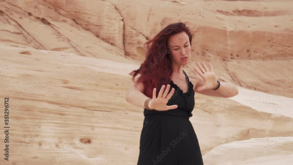 Beautiful redhead girl in black suit practice ecstatic dance in sandy desert Beautiful redhead girl in black suit practice ecstatic dance in sandy desert