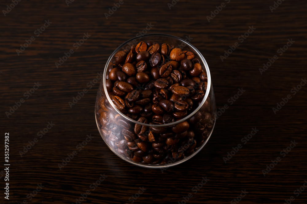 Fototapeta premium Coffee beans in a glass goblet isolated on a wooden background.