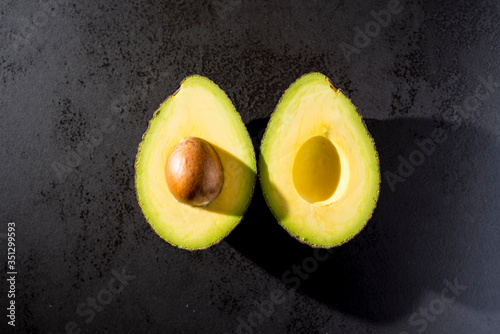 
avocado cut in half on black background