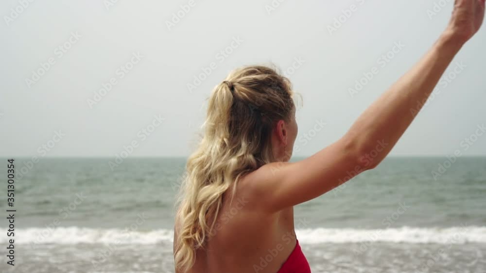 Young woman goes in for sports, does warm-up and exercises on the beach Young woman goes in for sports, does warm-up and exercises on the beach