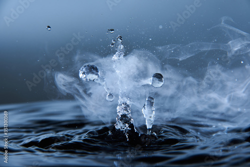 Boiling water splash with steam on dark blue background closeup photo