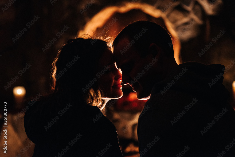 guy and girl are sitting on the background of a burning fireplace