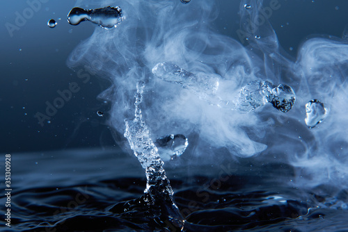 Foto Boiling water splash with steam on dark blue background closeup