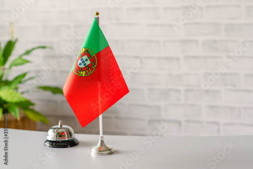 Silver vintage bell with national flag of Portugal on reception desk with copy space. Hotel service. Travel, tourism. Selective focus. Europe, Concept.