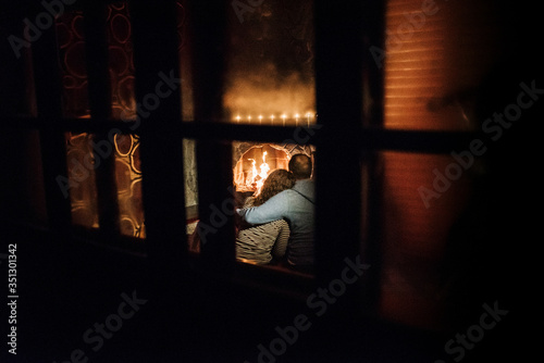 guy and girl are sitting on the background of a burning fireplace