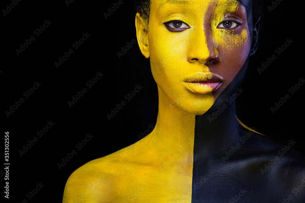 © Mike Orlov - Woman with black body paint. Cheerful young african girl with art bodypaint. An amazing model with yellow makeup. Closeup face.