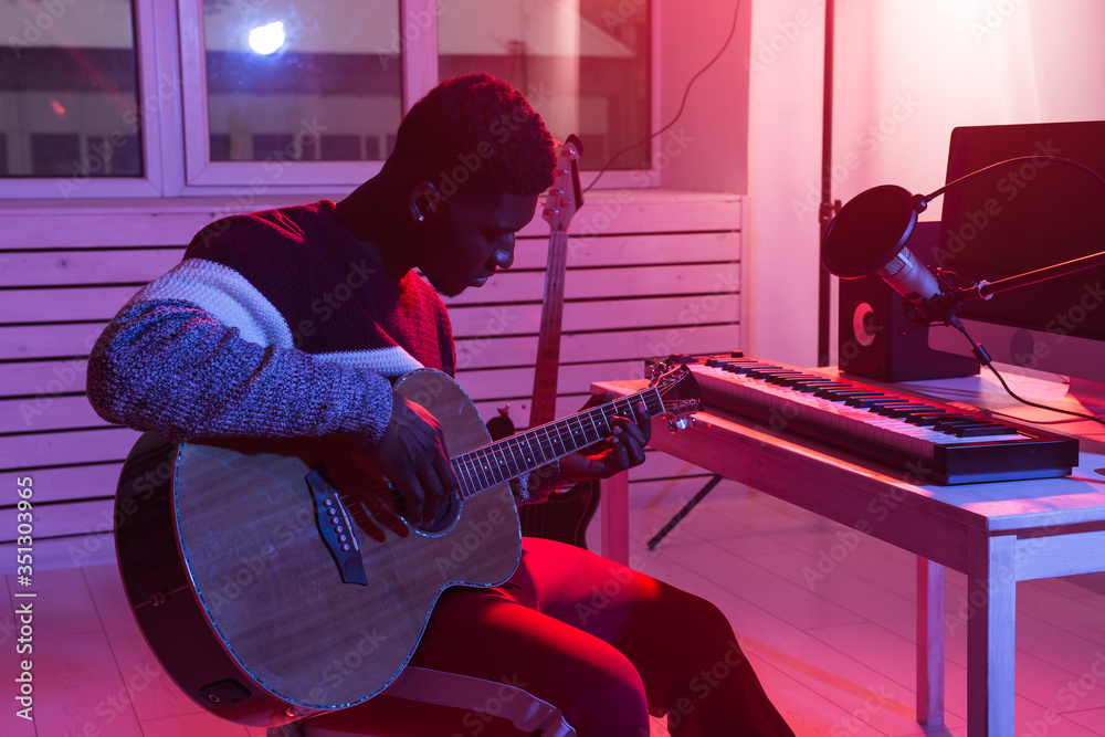 Obraz premium Create music and a recording studio concept - African american man guitarist recording electric guitar track in home studio