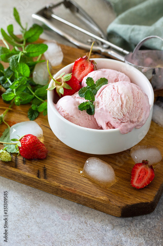 Homemade Organic Strawberry Ice Cream. Strawberry ice cream balls with mint leafon a light stone or slate table. Copy space.