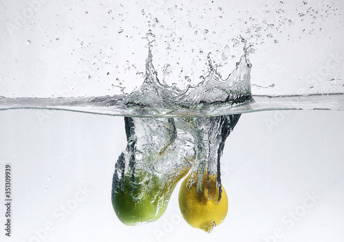 lemon and apple are falling into the water with bubbles and splash