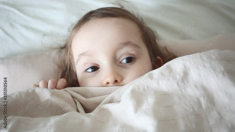 Girl having fun in a bed, she play with blanket. He is hiding and peeking out from under the blanket. Girl having fun in a bed, she play with blanket. He is hiding and peeking out from under the blanket.