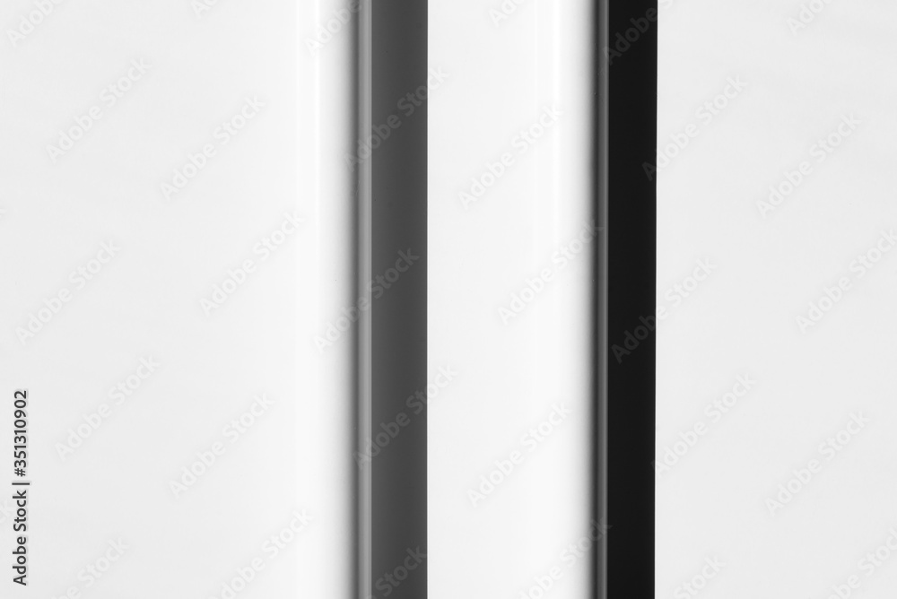 Two white tubes with shadows, arranged in regular, parallel lines. Modern background. White, grey and black. Copy space. Two white tubes with shadows, arranged in regular, parallel lines. Modern background. White, grey and black. Copy space.