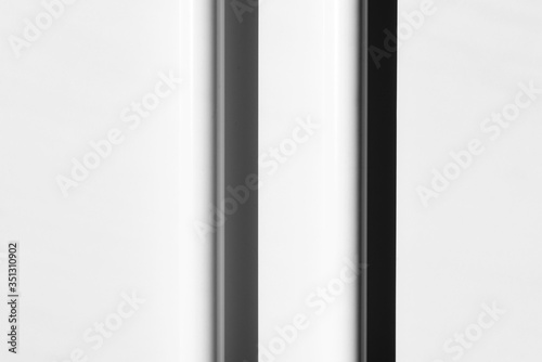 Two white tubes with shadows, arranged in regular, parallel lines. Modern background. White, grey and black. Copy space.