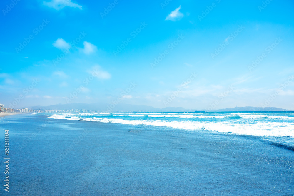 Blue ocean waves and yellow sand