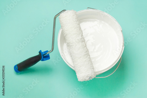 House repair, roller with a bucket of white paint