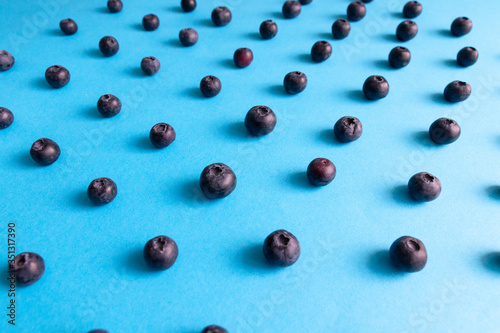 Fresh ripe blueberry berries pattern on blue background.