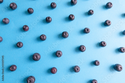 Fresh ripe blueberry berries pattern on a blue background.