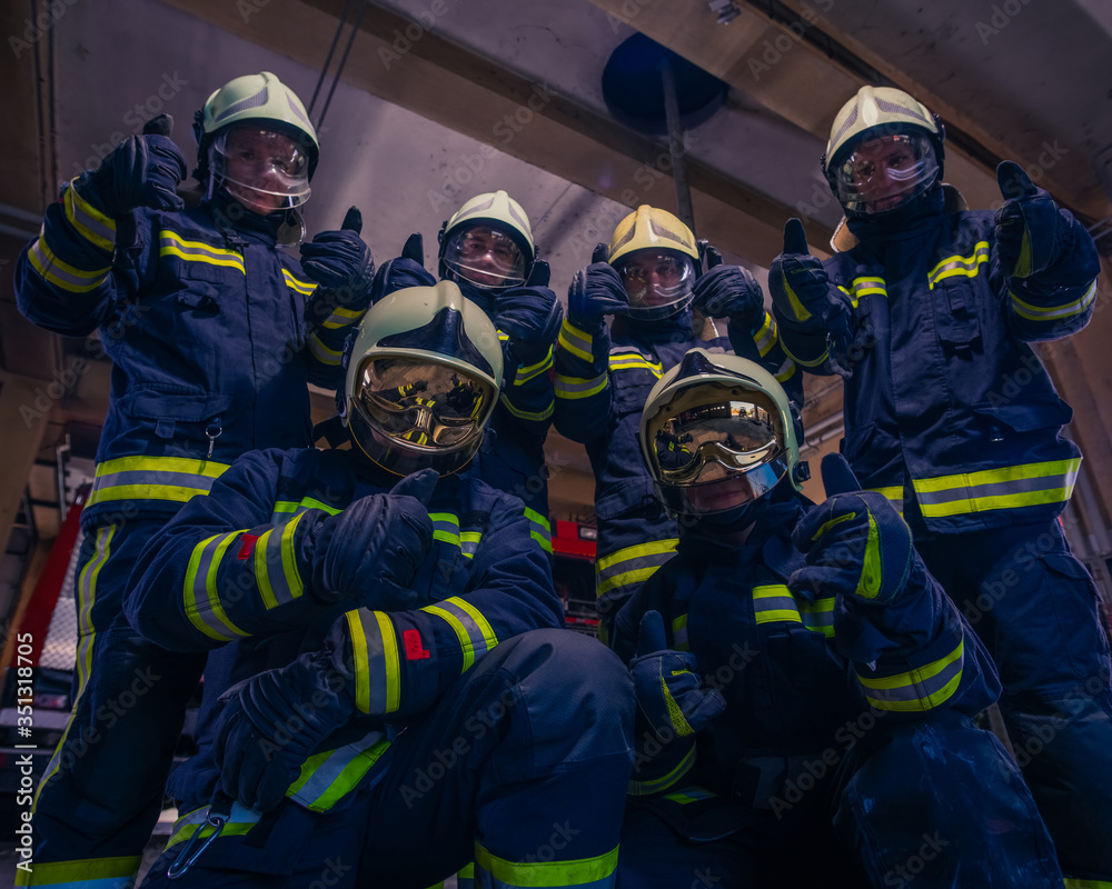 Portrait of group of firefighters wearing protective uniform inside the fire station Portrait of group of firefighters wearing protective uniform inside the fire station