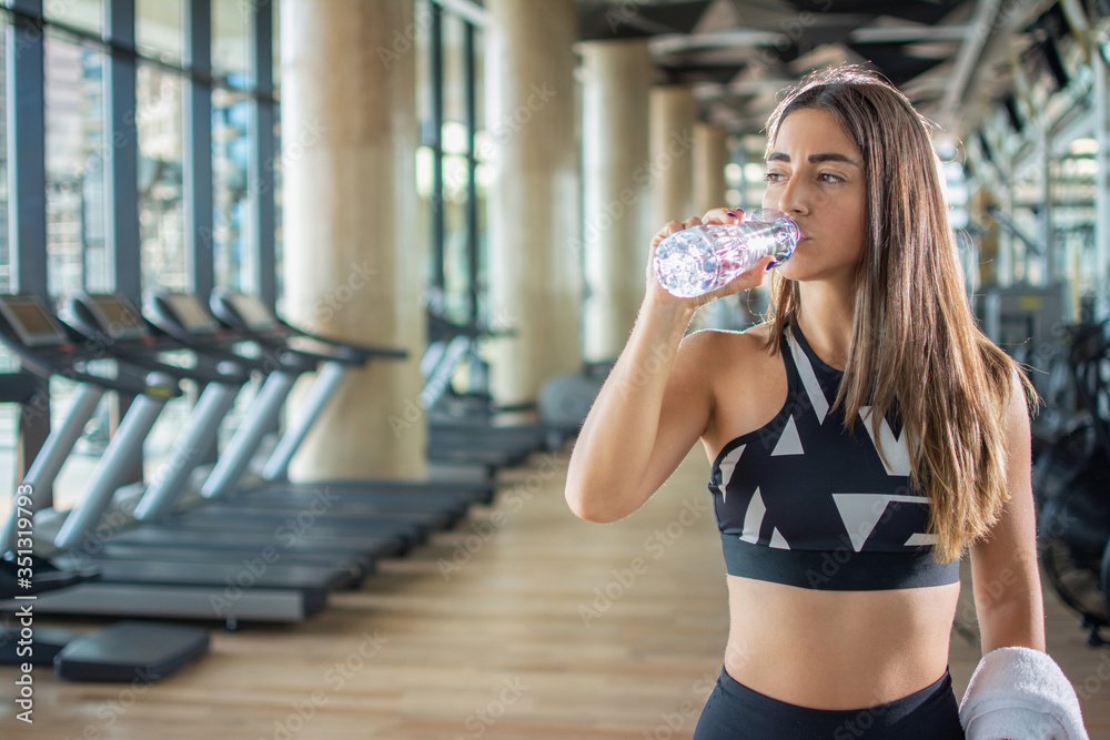 Fototapeta premium Piękna młoda kobieta fit wody pitnej po treningu na siłowni.