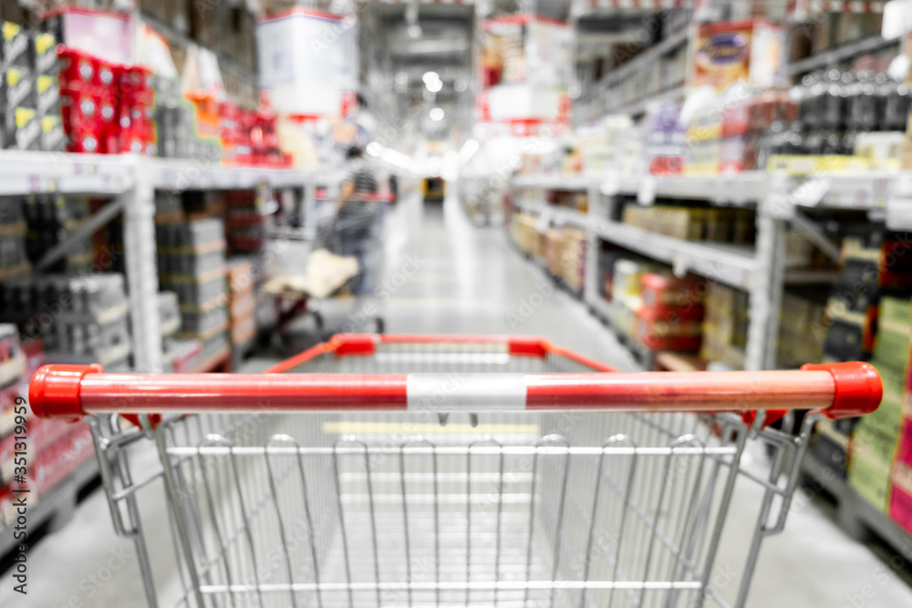 The empty red shopping cart in supermarket with blurred background. The empty red shopping cart in supermarket with blurred background.
