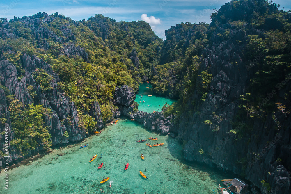 An aerial view of tourists kayaking going in and out in the Small Lagoon to Big Lagoon in Maniloc Island, El Nido, Palawan, Philippines.