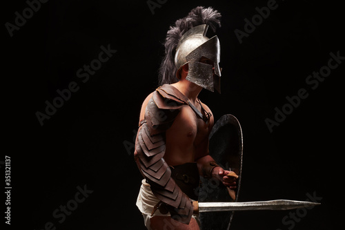 Gladiator with sword and armor on a black background © matyuschenko