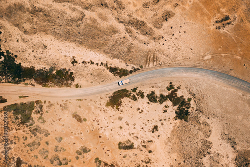 Aerial view of cargo truck driving on gravel road in arid desert climate, Majanicho, Fuerteventura island. photo