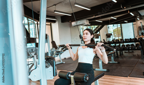 Young beautiful woman in sportswear working out with machine in gym