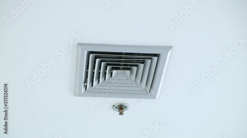 Air vent on a ceiling, pans to air vent cover on office ceiling, Plastic ventilation grid, piece of home ventilation system. cooling ventilation. photo