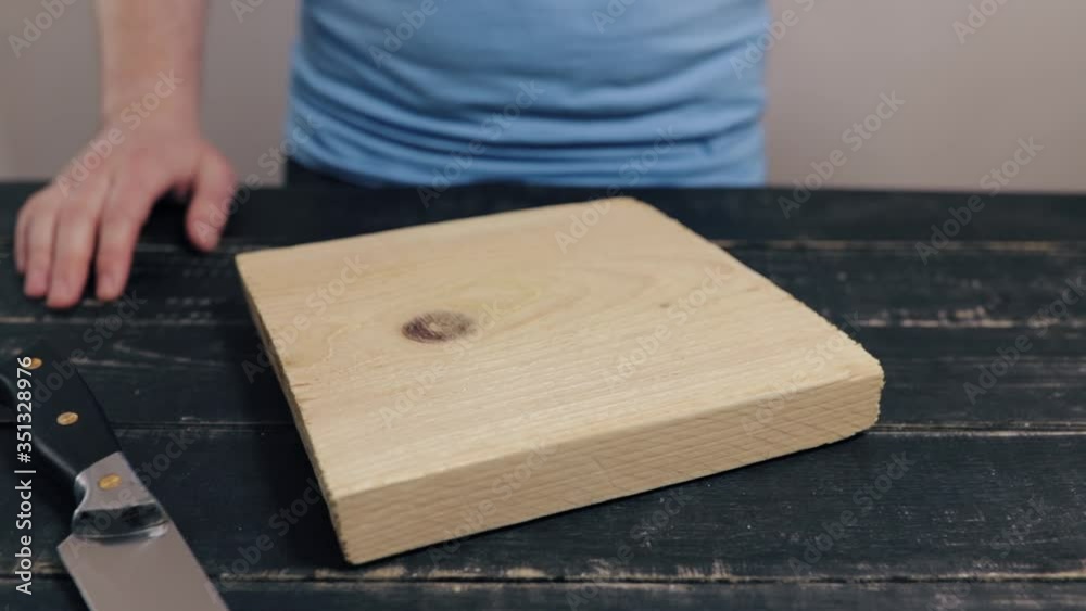 Man at black table cutting halva in two halves on chopping wooden kitchen board. Unhealthy fat food concept.